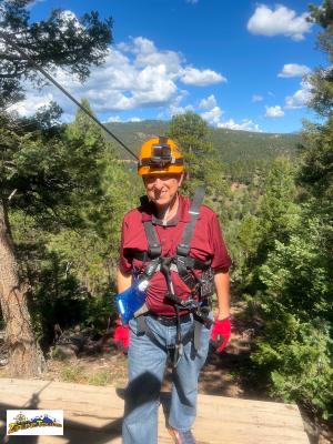 Guest zipping over the Rocky Mountain forest canopy