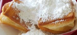 A plate of fluffy beignets with powdered sugar