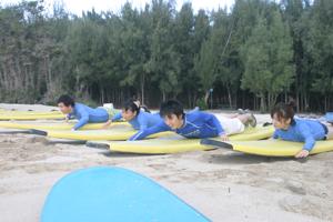 A group of people getting a surfing lesson on an Oahu beach